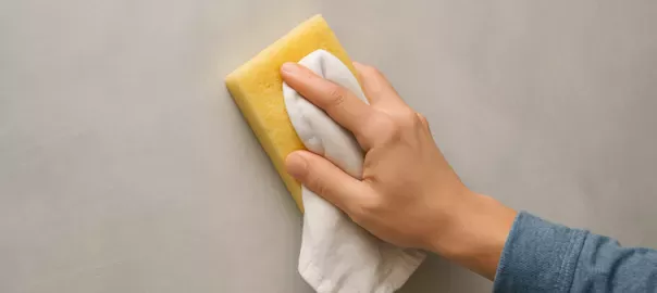 "Person rengör vägg målad med kalkfärg eller kritfärg med mjuk svamp och lätt fuktad trasa – skonsam rengöring som bevarar den matta ytan och naturliga strukturen"